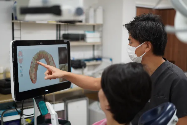 モニターを指差しながら患者さんに説明している歯科医師